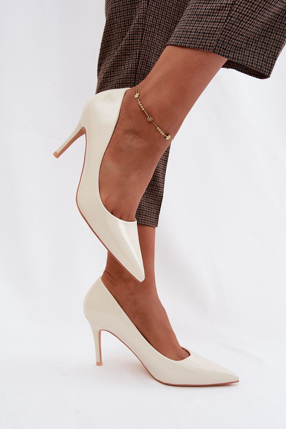 White high-heeled shoes worn with a plaid skirt on a white background