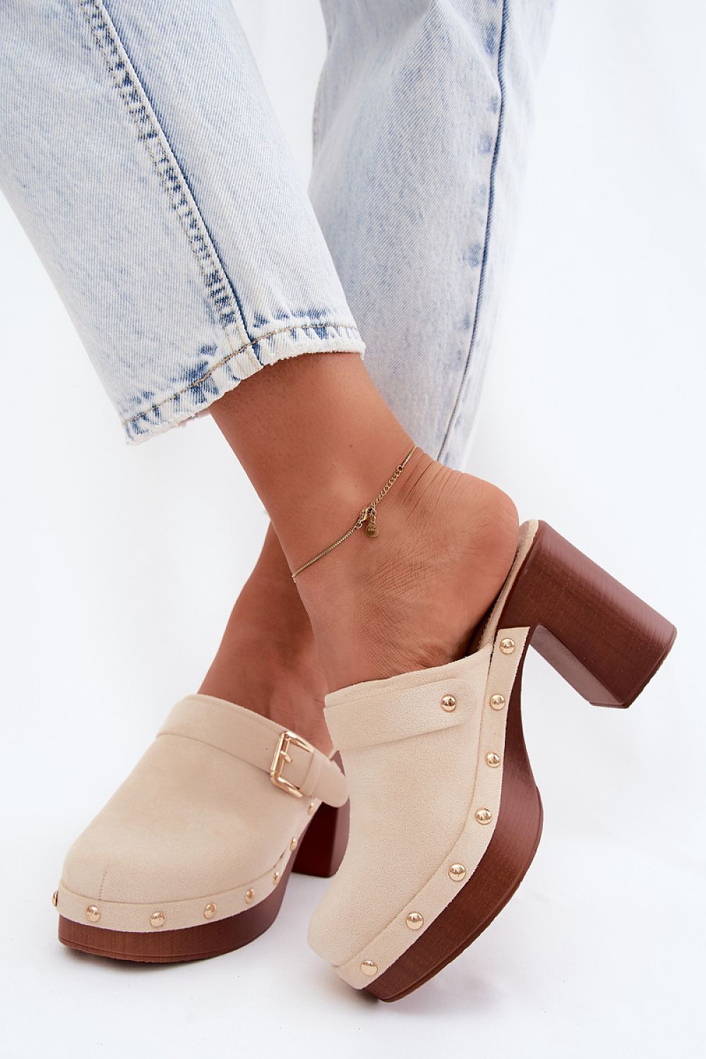 Beige clogs with brown block heels worn with light blue jeans on a white background