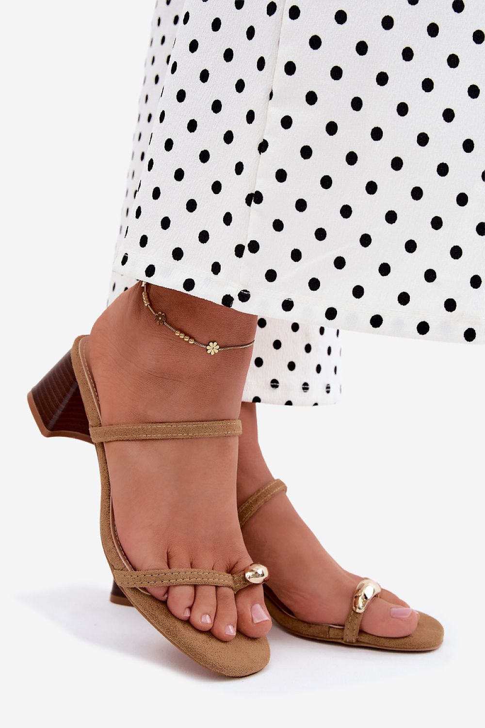 Brown sandals worn with a polka dot skirt on a white background