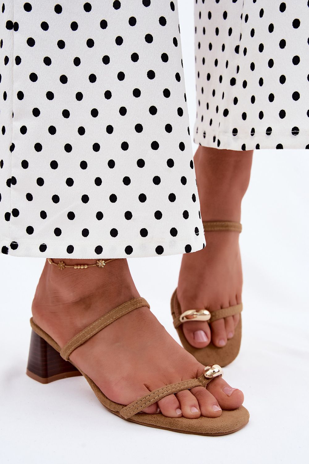 Brown sandals worn with a polka dot dress on a white background