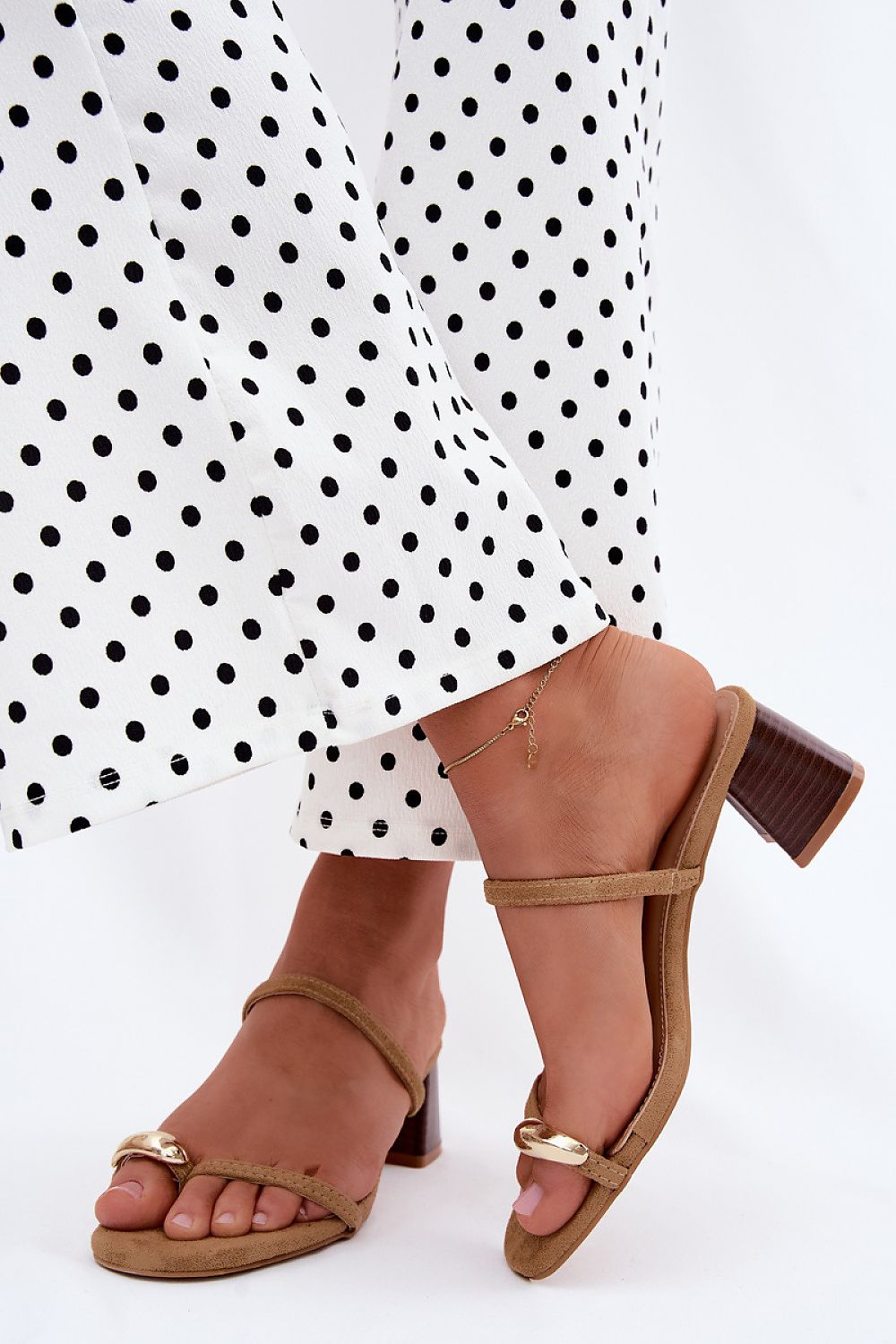 Brown sandals worn with a white polka dot dress on a white background