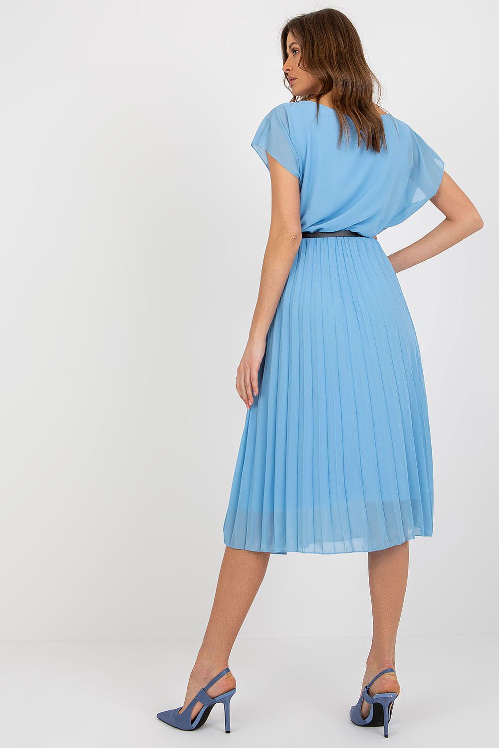 Woman wearing a light blue pleated dress on a white background