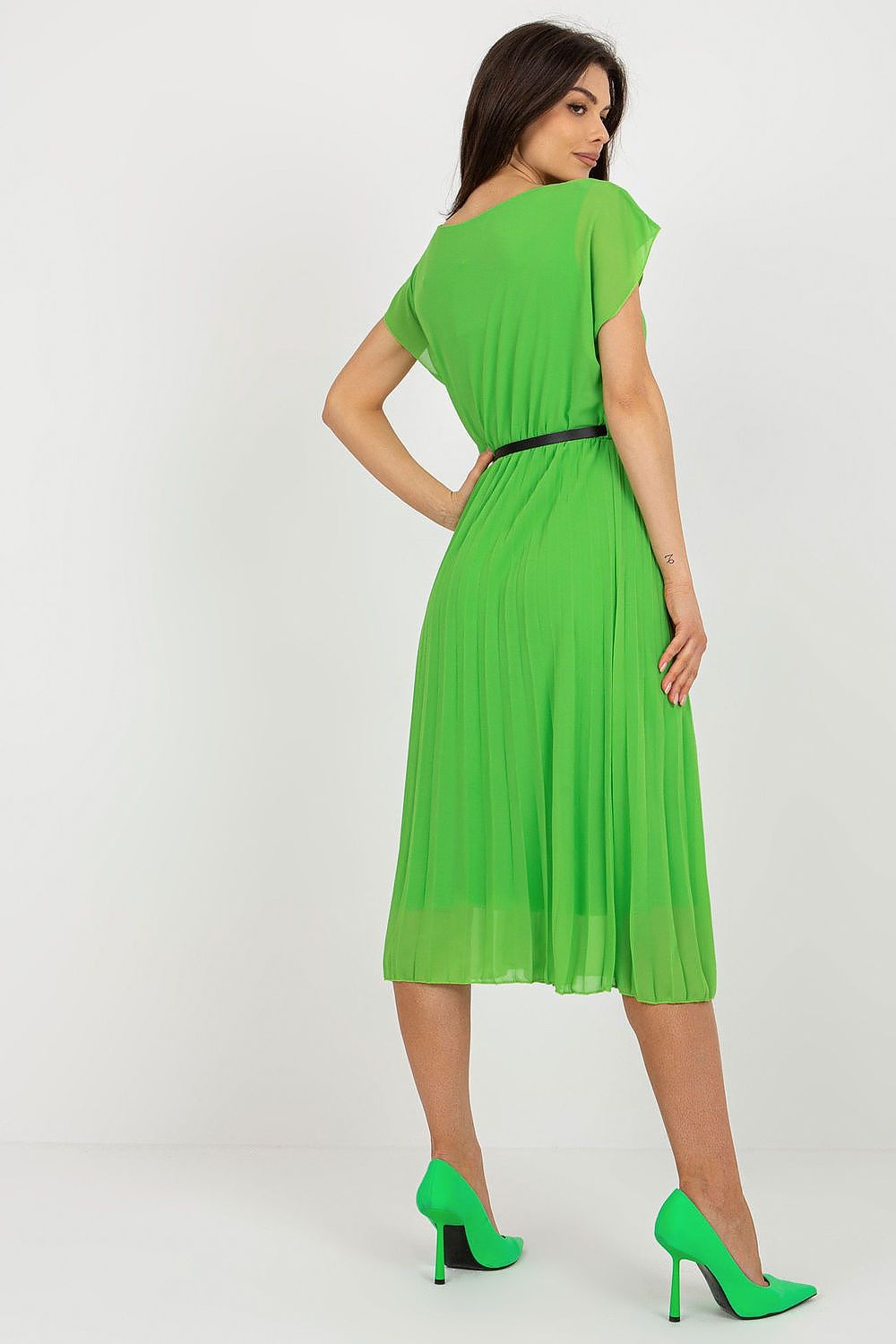 Woman wearing a green dress with a plain background