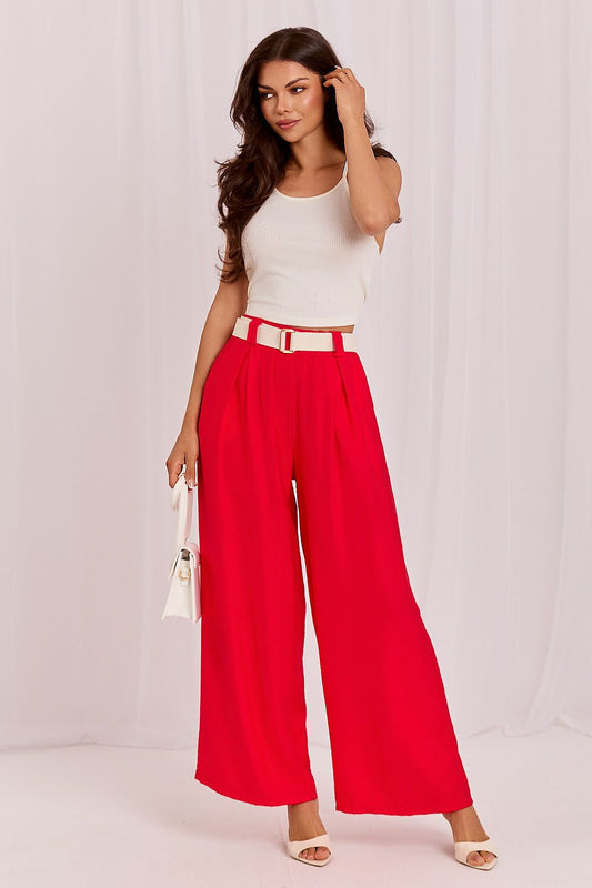 Woman wearing a white top and red pants against a white background
