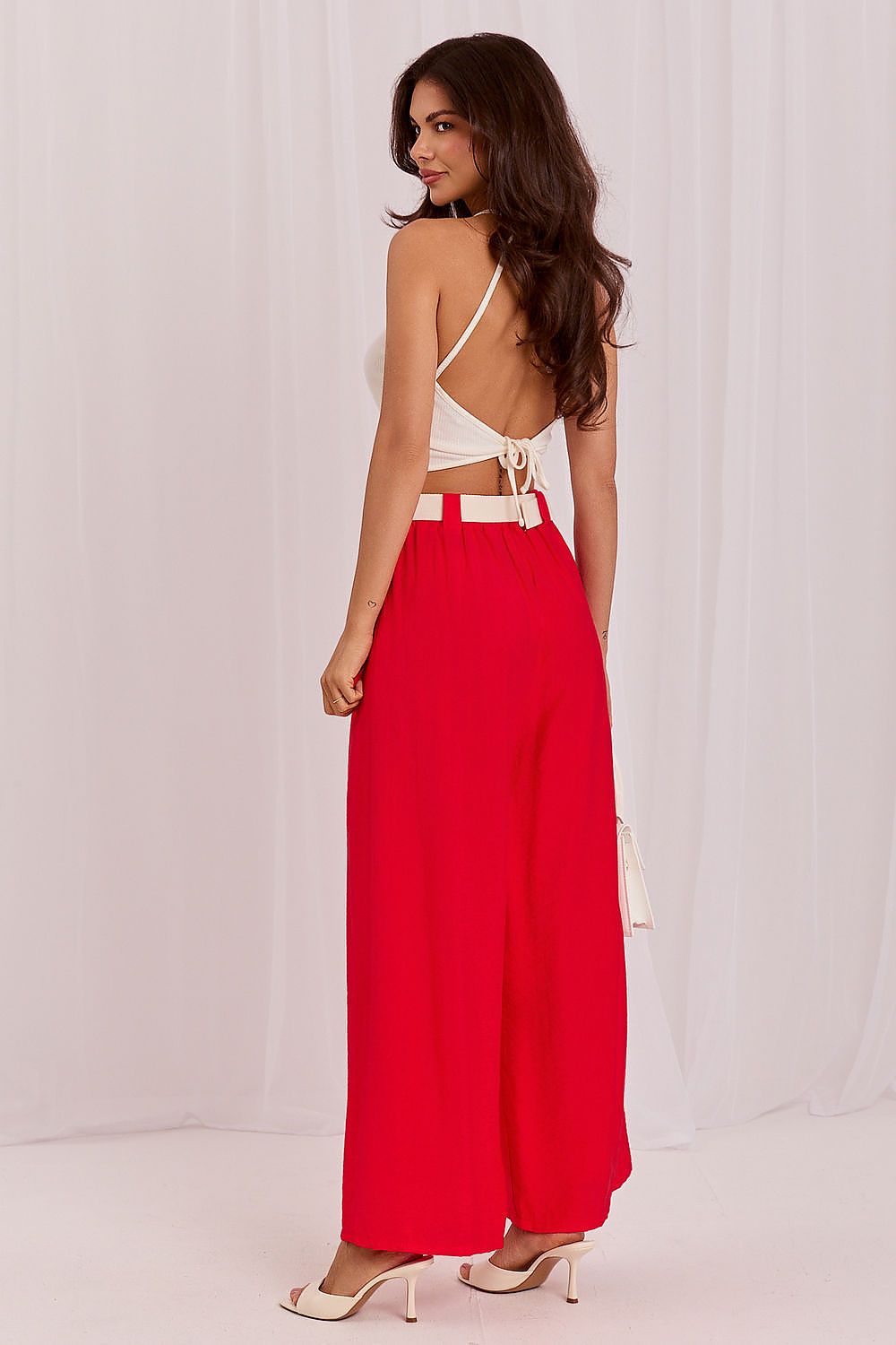 Woman wearing a white top and red pants against a white background