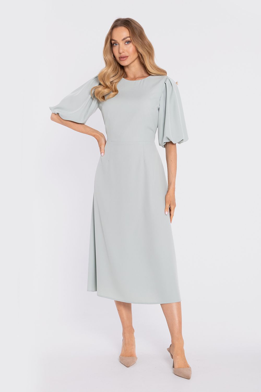 Woman wearing a light gray dress with ruffled sleeves on a white background