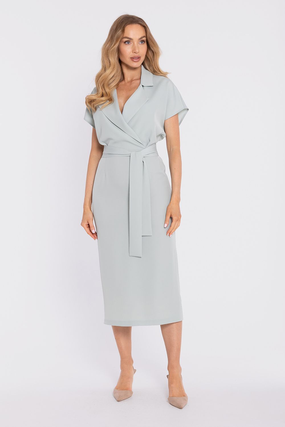 Woman wearing a light gray dress with a belt on a white background