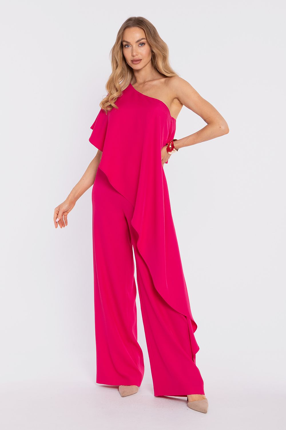Woman wearing a bright pink one-shoulder jumpsuit on a white background