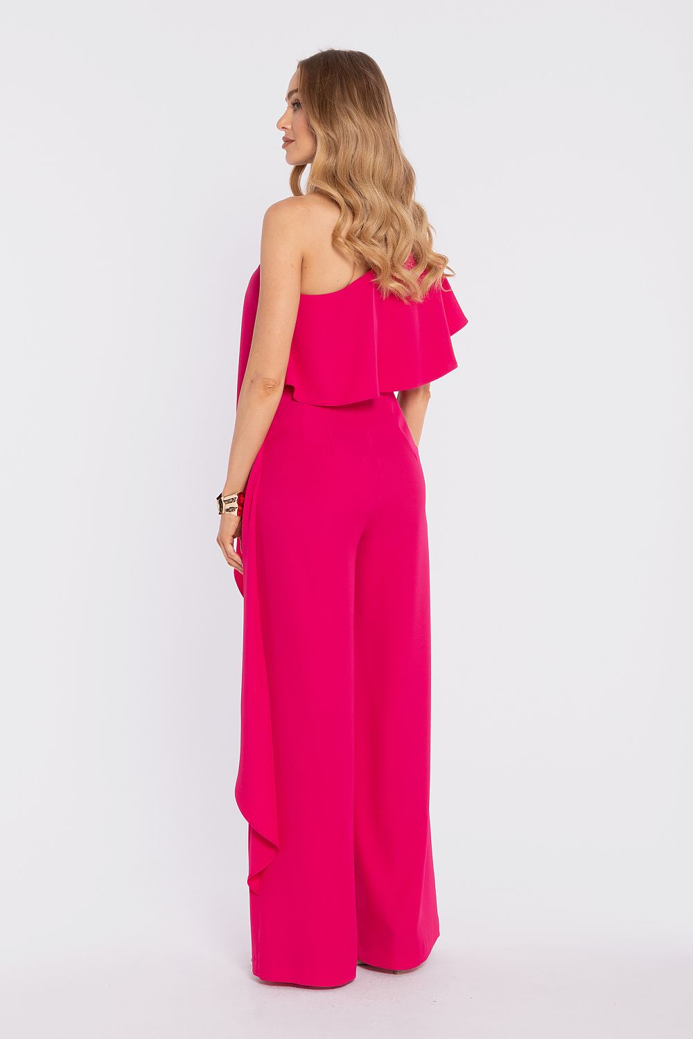 Woman wearing a bright pink jumpsuit on a white background