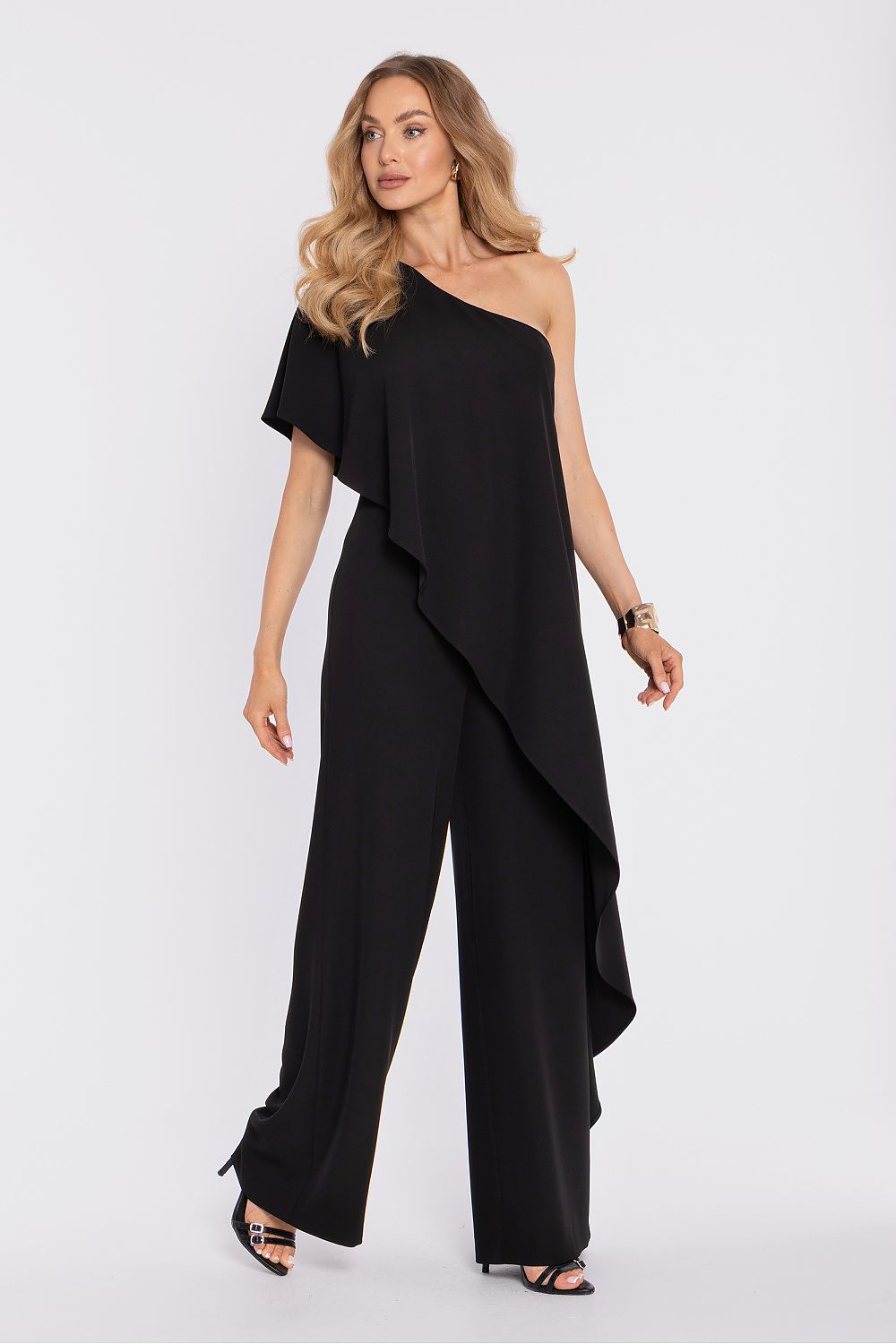 Woman wearing a black one-shoulder jumpsuit on a white background