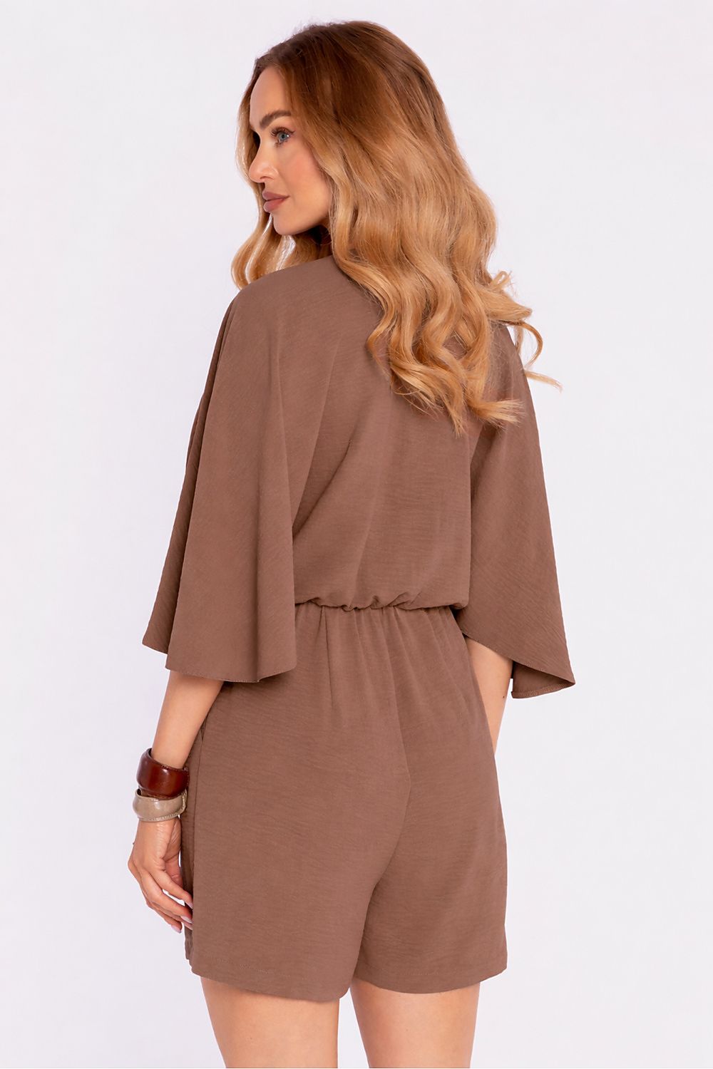 Woman wearing a brown romper with a plain background