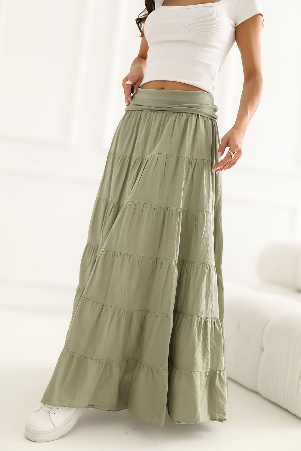 Woman wearing a white top and green tiered skirt on a white background