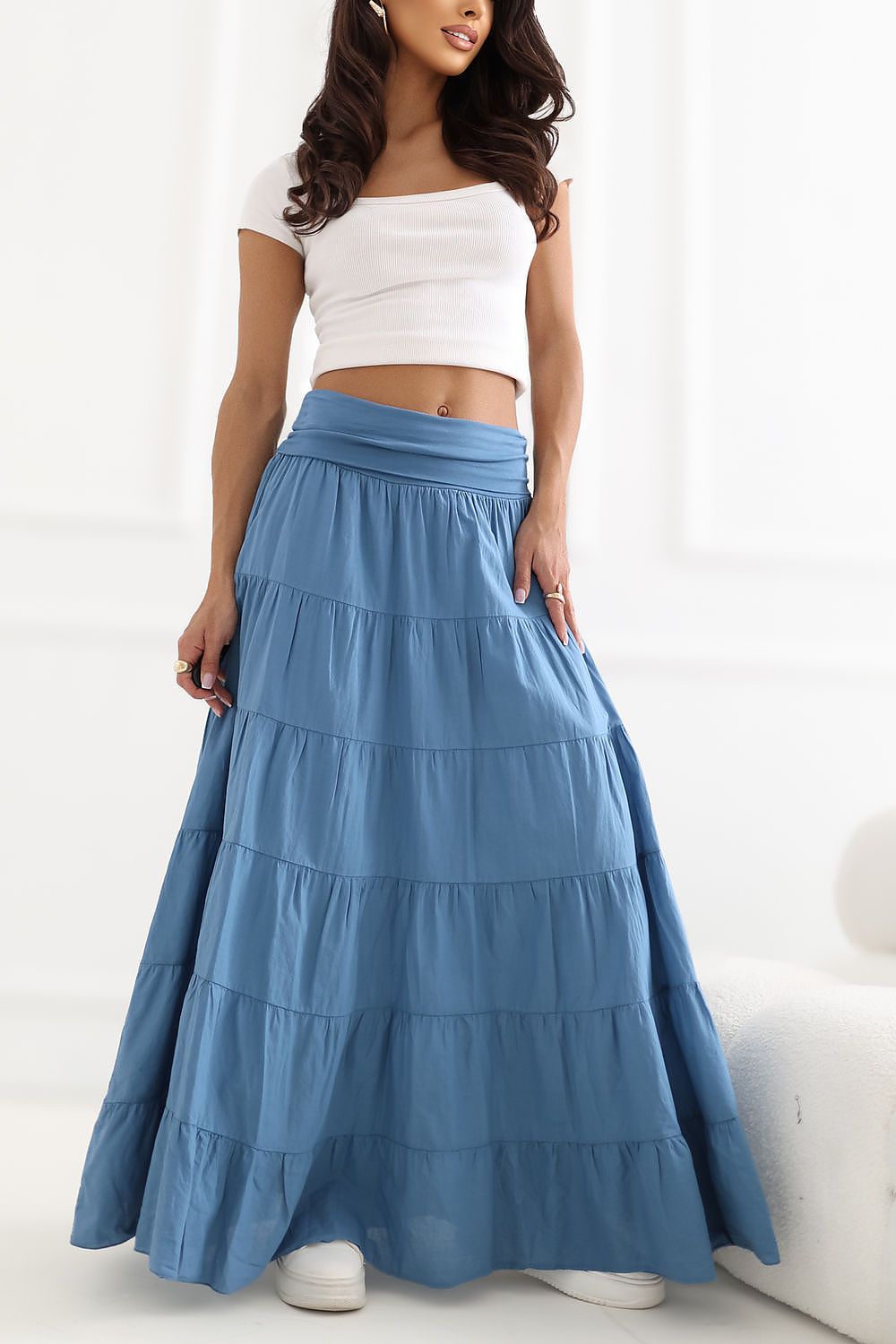 Woman wearing a white top and blue tiered skirt on a white background