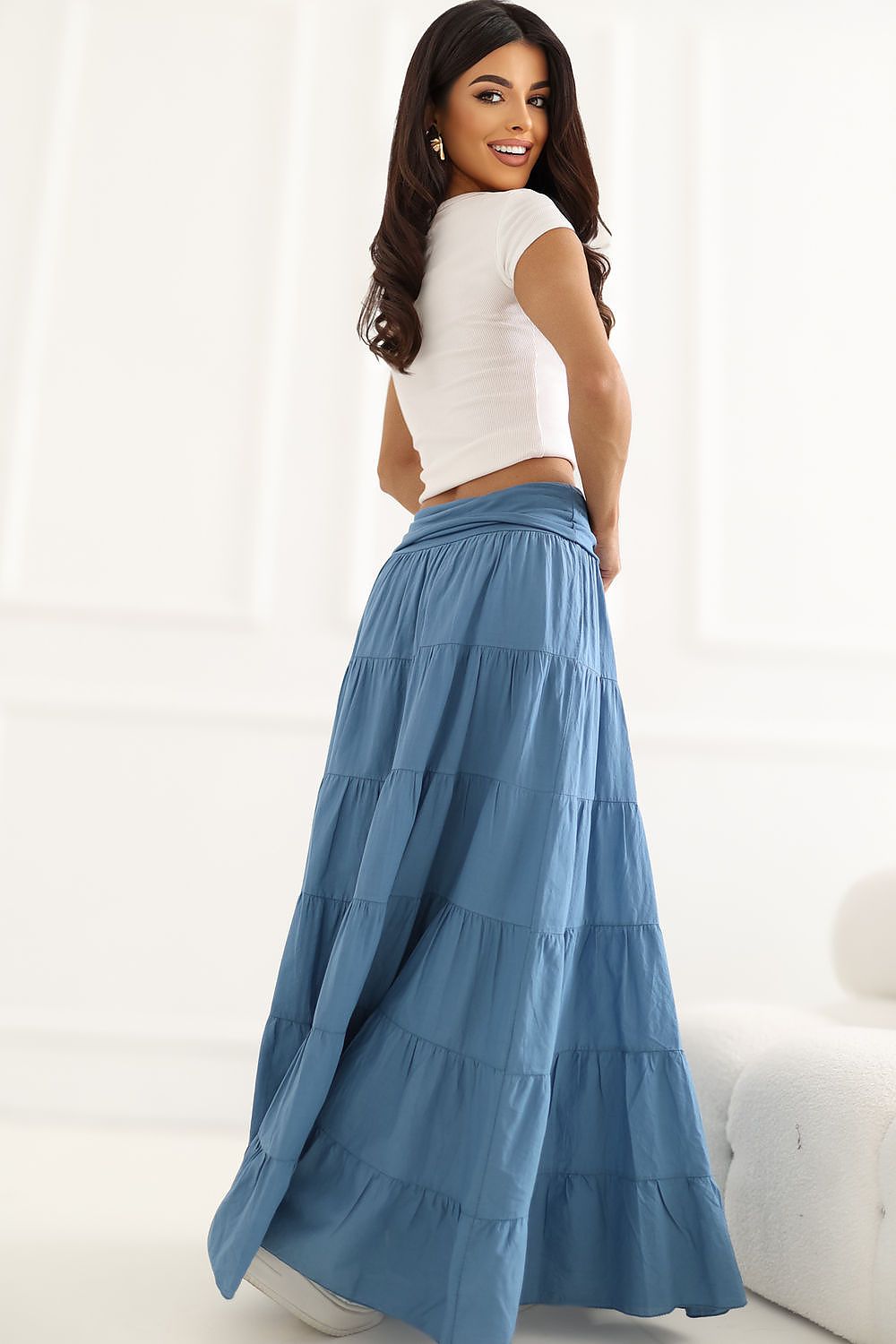 Woman wearing a white top and blue tiered skirt on a white background