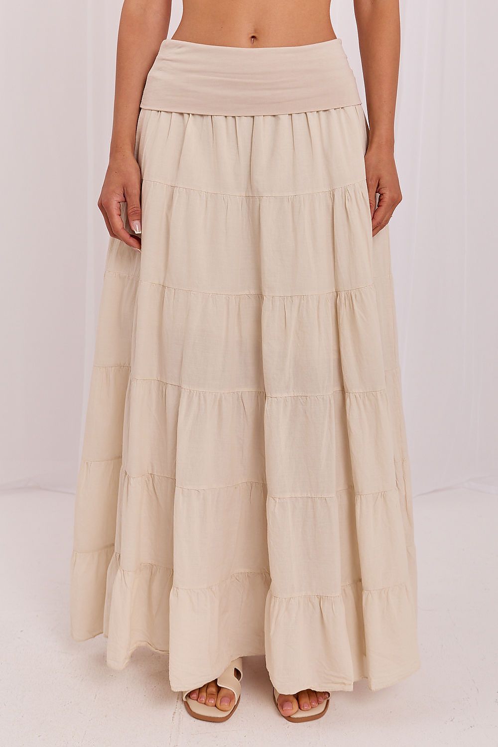 Beige tiered skirt worn by a person on a white background