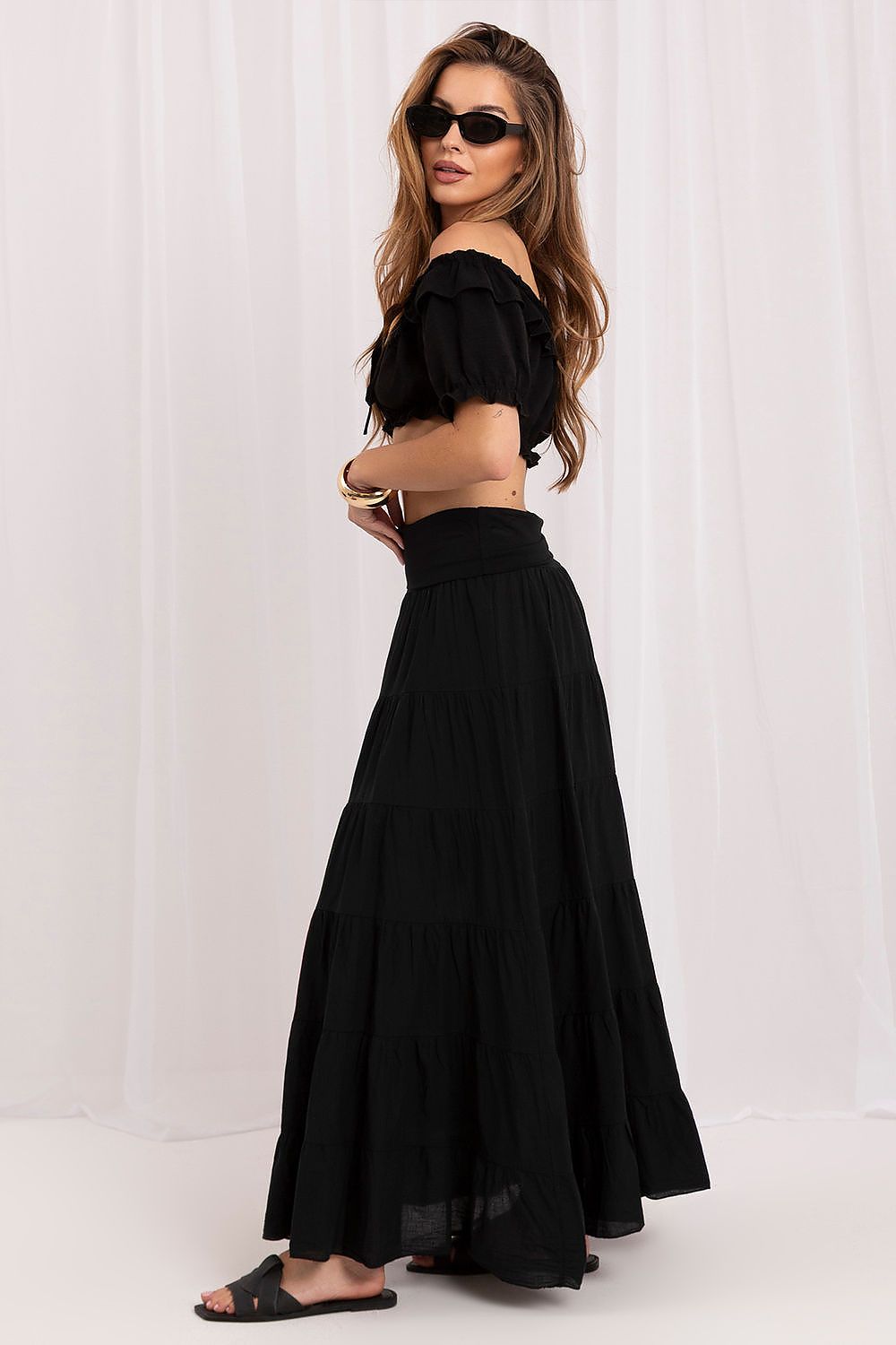 Woman wearing a black outfit with sunglasses on a white background