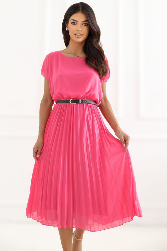 A woman modeling a bright pink midi dress with short sleeves, a round neckline, and a pleated skirt, cinched at the waist with a thin black belt with a silver buckle.