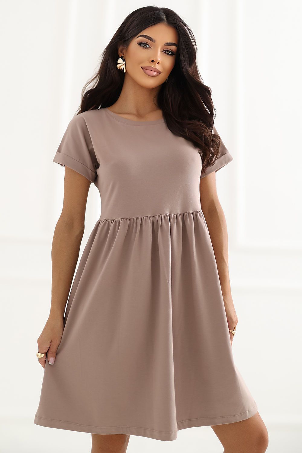 A woman modeling a short-sleeve, knee-length shift dress in a muted taupe-brown color against a bright white background.