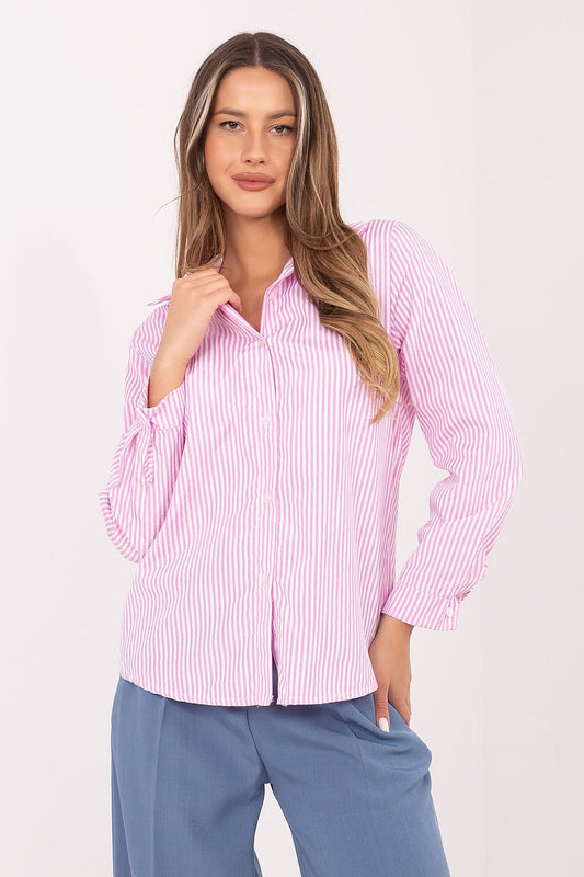 A woman modeling a pink and white vertically striped button-up shirt with long sleeves, paired with blue pants, against a plain light background.