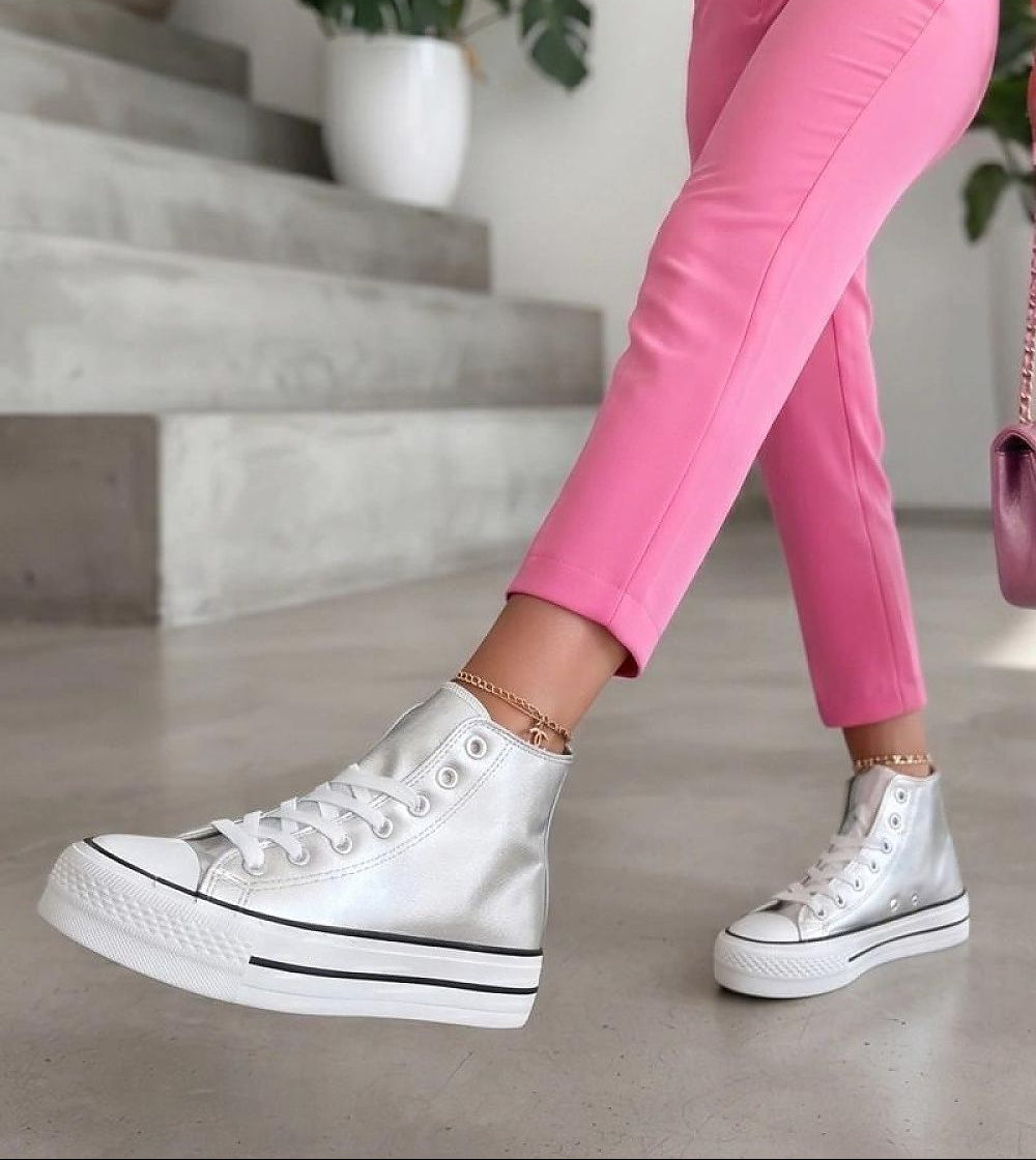 White high-top platform sneakers with silver metallic toe caps, worn with pink cropped leggings in an indoor setting with concrete steps.