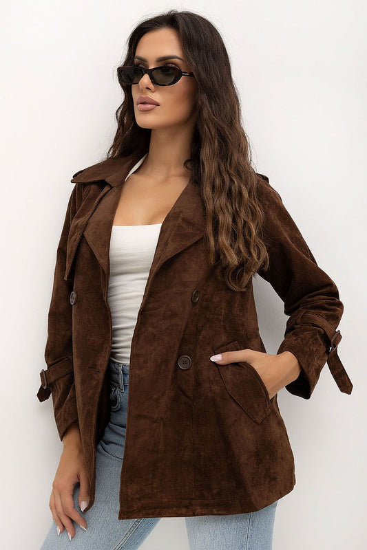 A woman wearing a brown suede-like double-breasted blazer over a white top and light blue jeans, styled with black sunglasses against a plain white background.