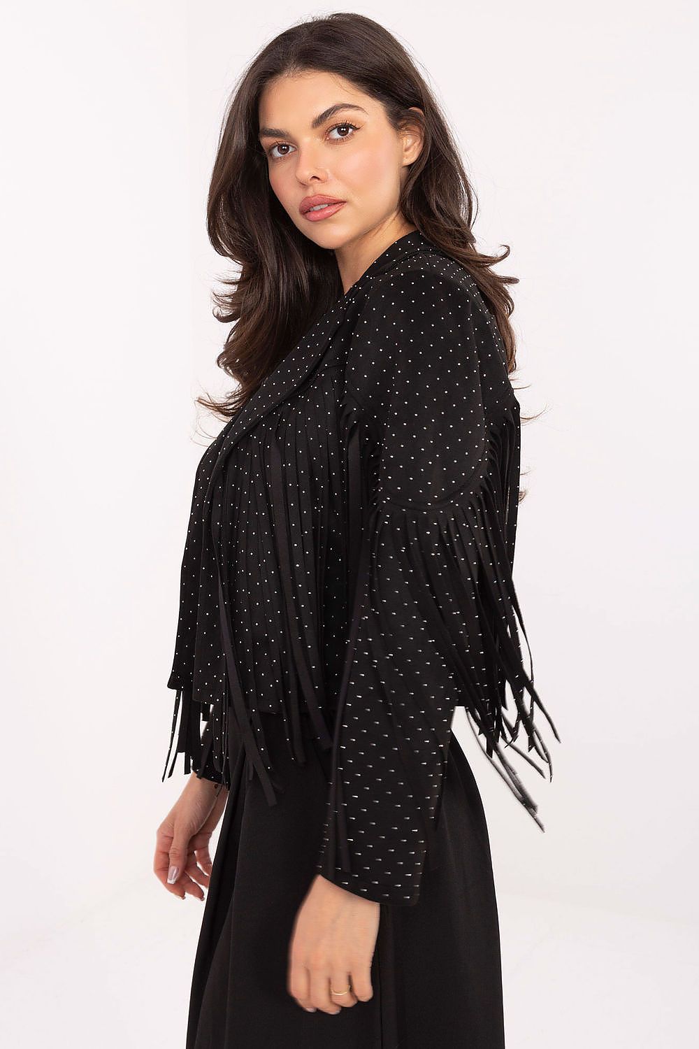 A woman modeling a black fringed wrap jacket with small white polka dots, shown from a three-quarter back view against a plain white studio background.