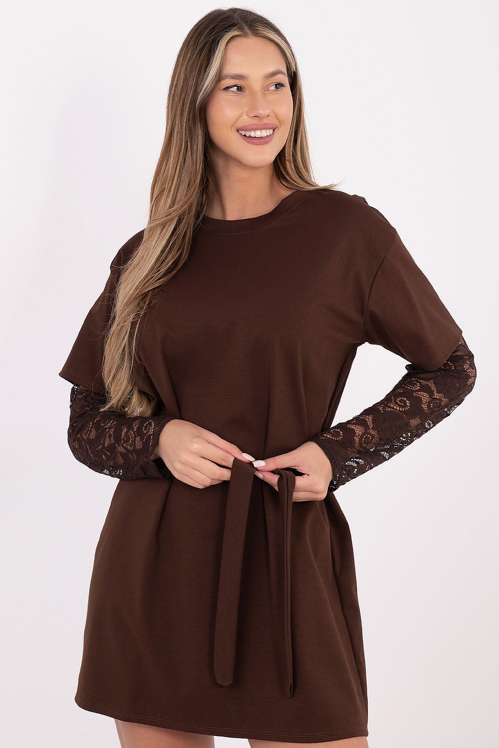 A woman modeling a brown long-sleeve dress with a solid crew neck and waist tie, featuring sheer lace sleeves, against a plain white background.