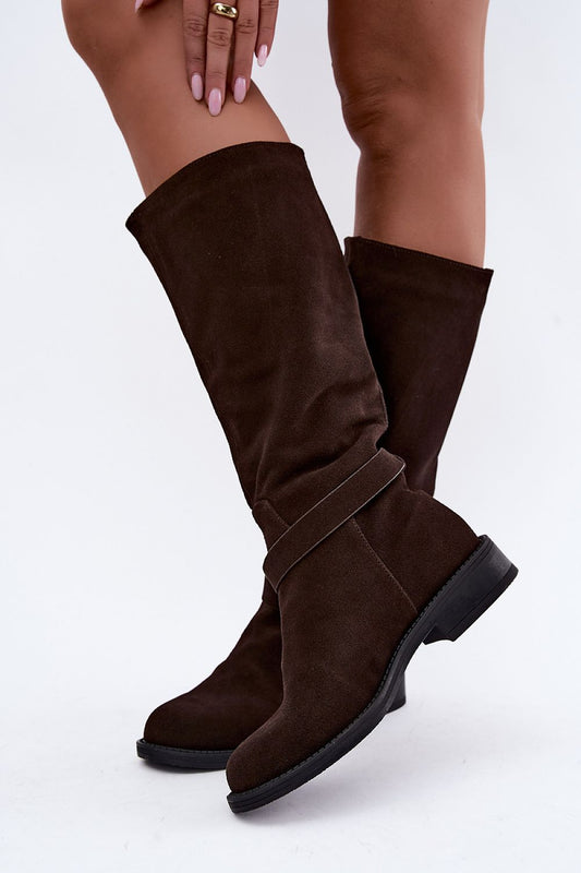 A pair of dark brown suede knee-high boots with a wrap-around strap detail, shown on a model's legs against a plain white background.