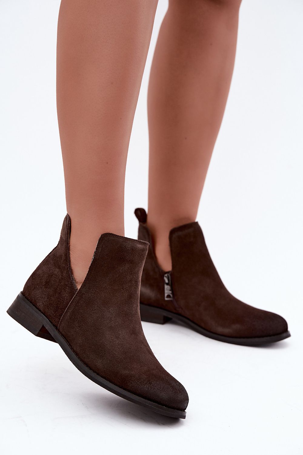 Dark brown suede Chelsea-style ankle boots worn on a model's feet, shown against a clean white studio background.