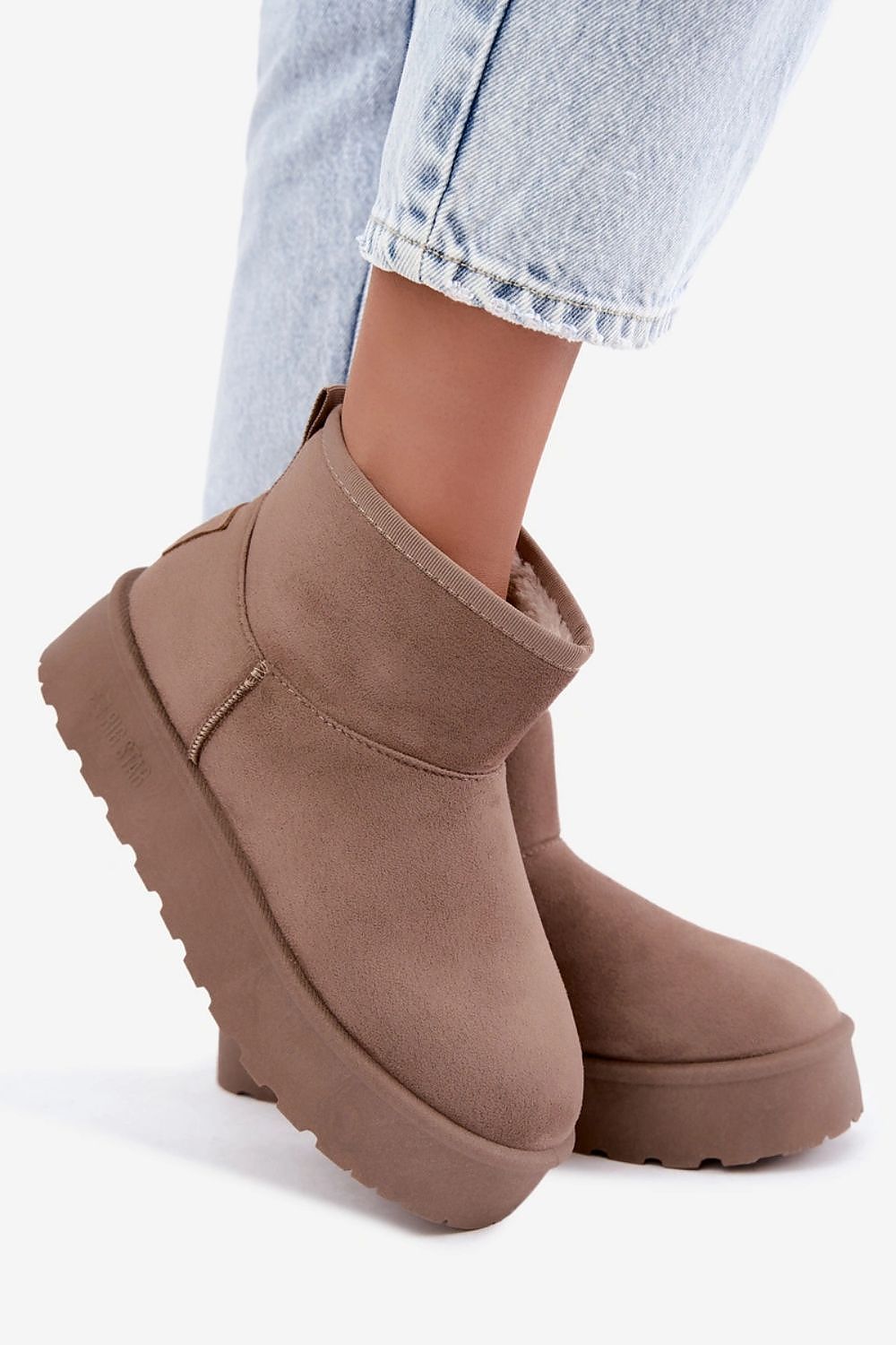 Taupe brown suede platform ankle boots worn with light wash blue jeans, shown from a side angle against a clean white background.
