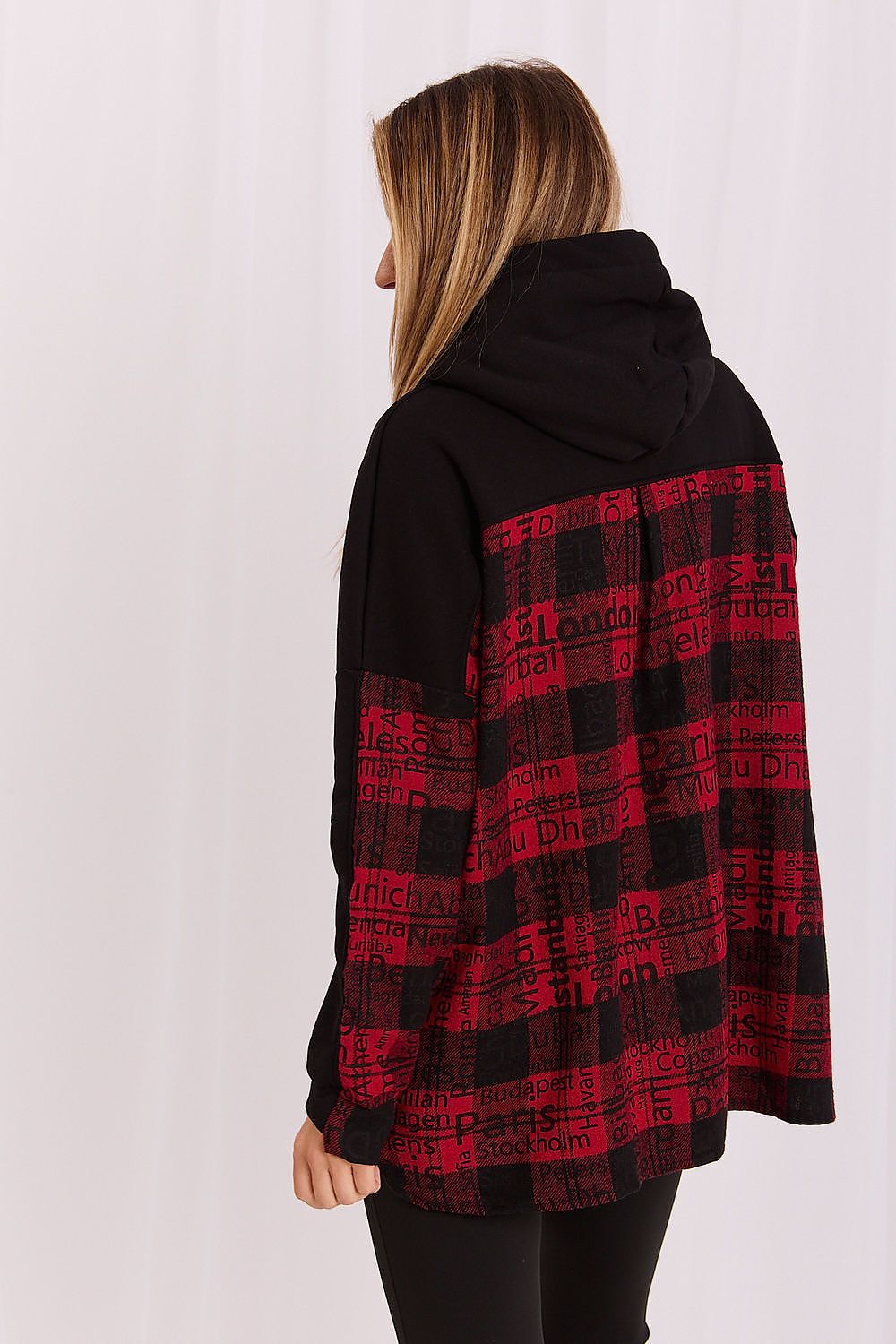A woman shown from the back wearing a black and red hooded sweatshirt with a red text pattern on the back and sleeves, paired with black pants, against a white studio background.