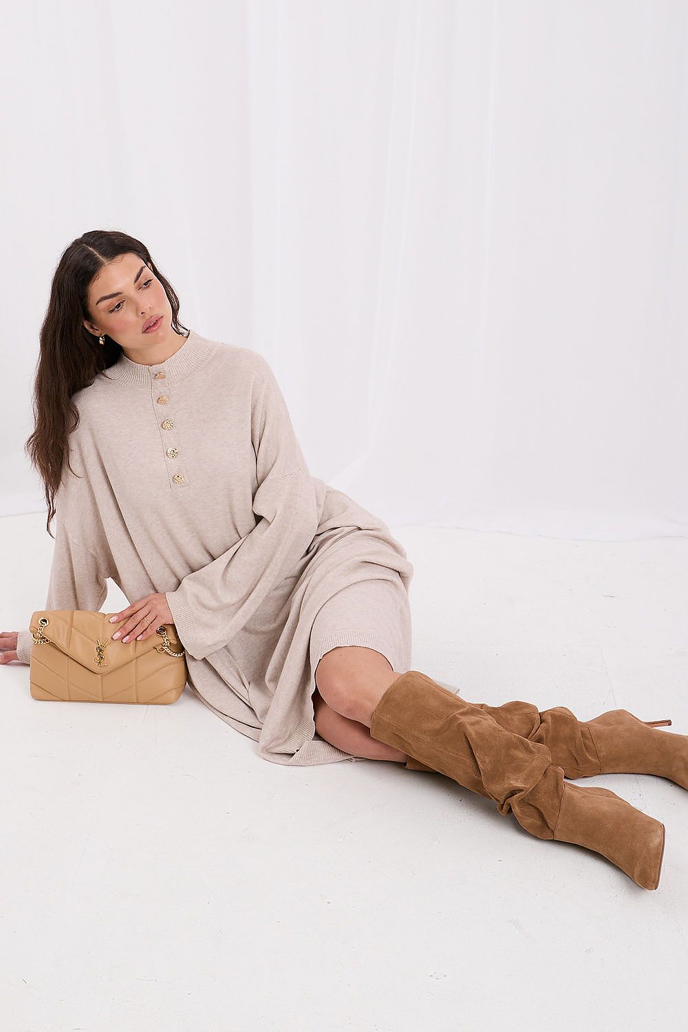  The Elowen Beige Oversized Knit Sweater Dress featuring a relaxed fit, long sleeves, stand-up collar and decorative front buttons.