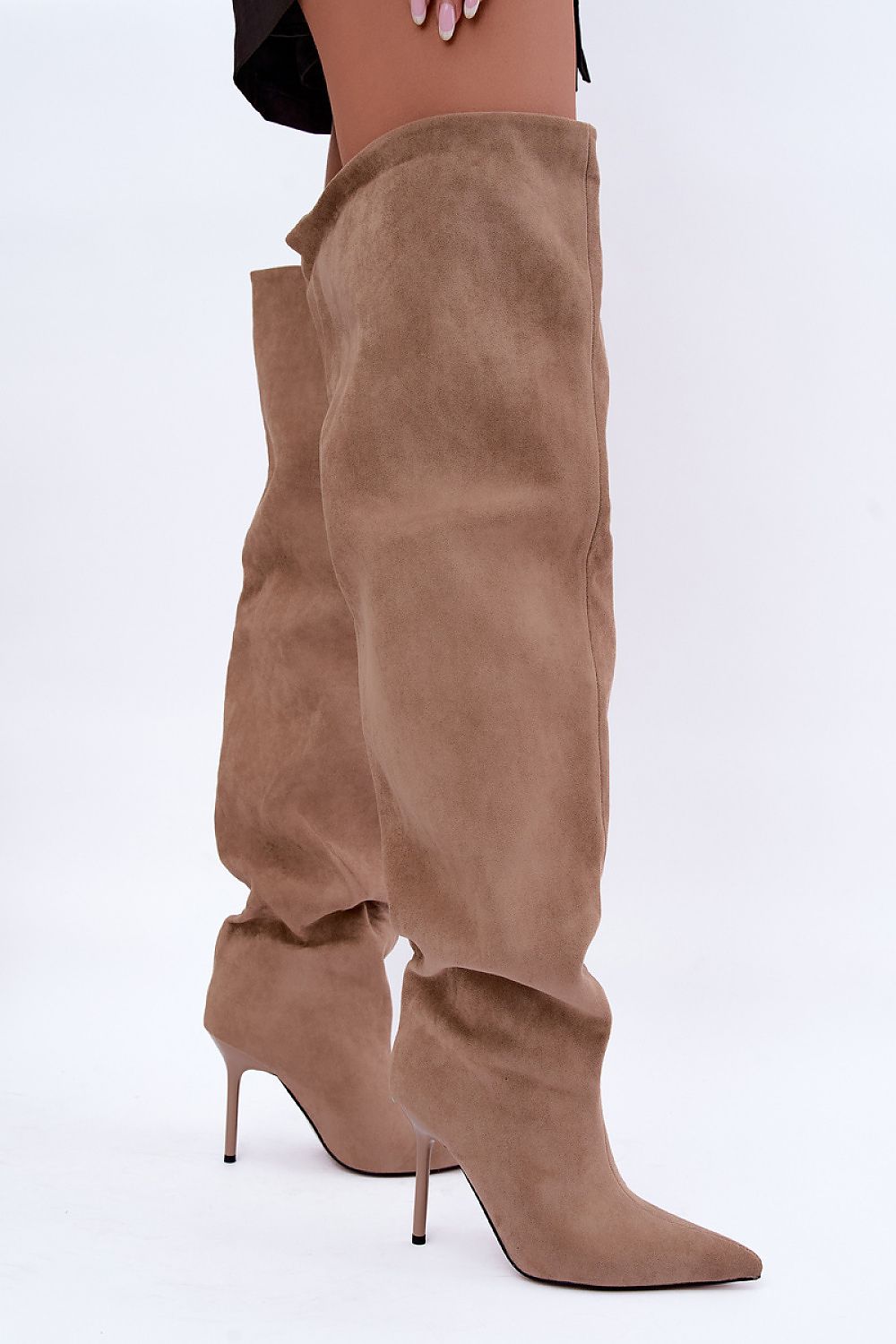 A pair of knee-high taupe suede boots with pointed toes and slim stiletto heels, shown on a model against a plain white background.