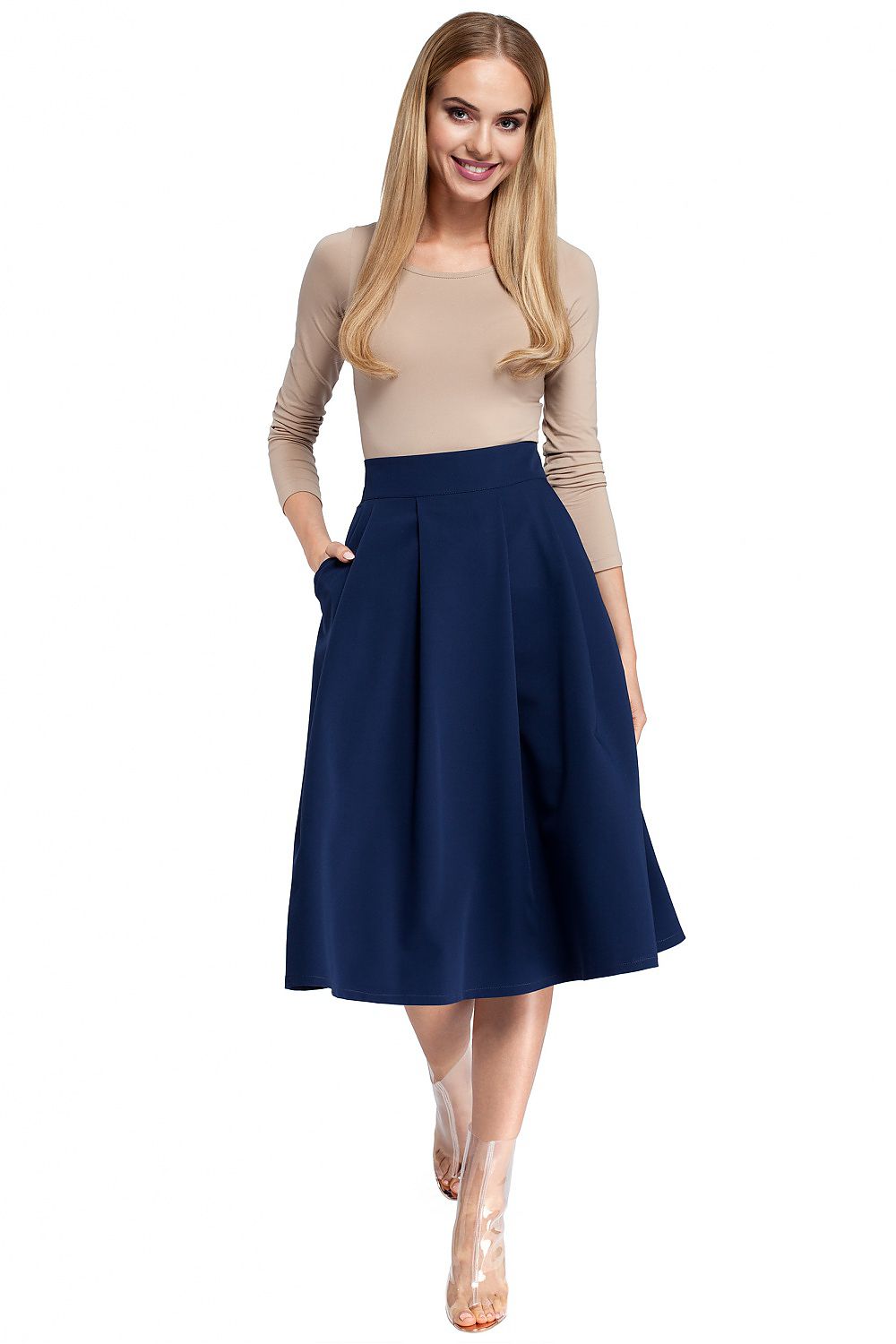 Woman wearing a beige top and navy blue skirt on a white background