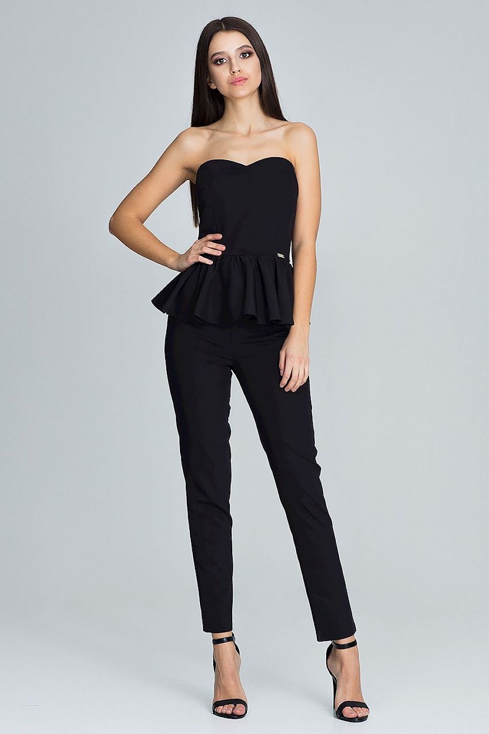 Woman wearing a black strapless top and black pants on a gray background