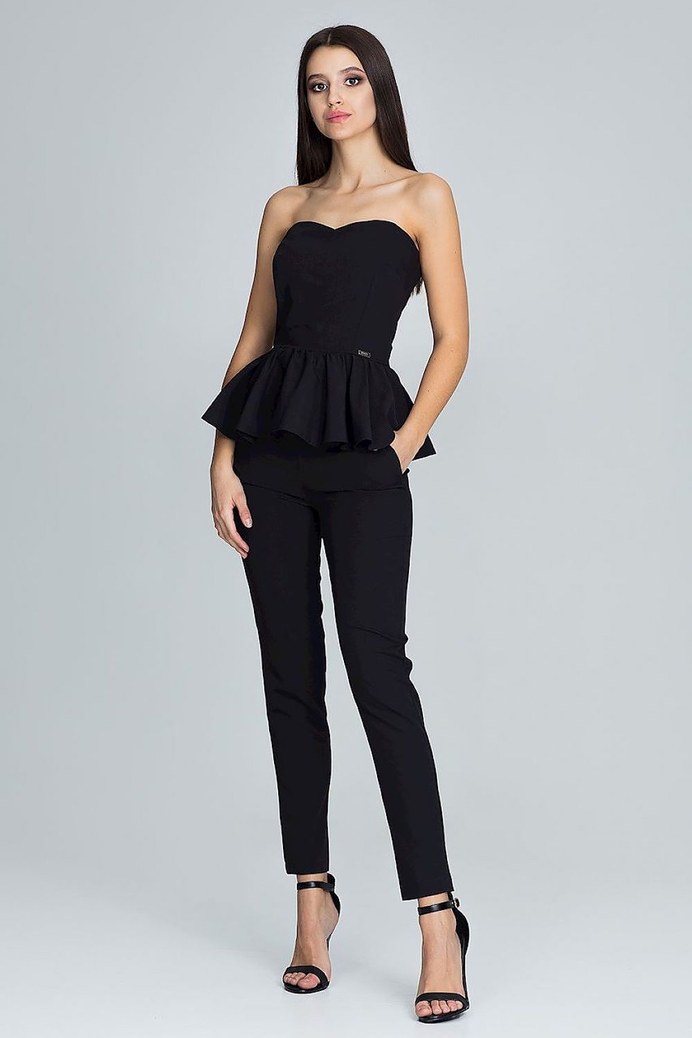 Woman wearing a black strapless peplum top and black pants on a gray background