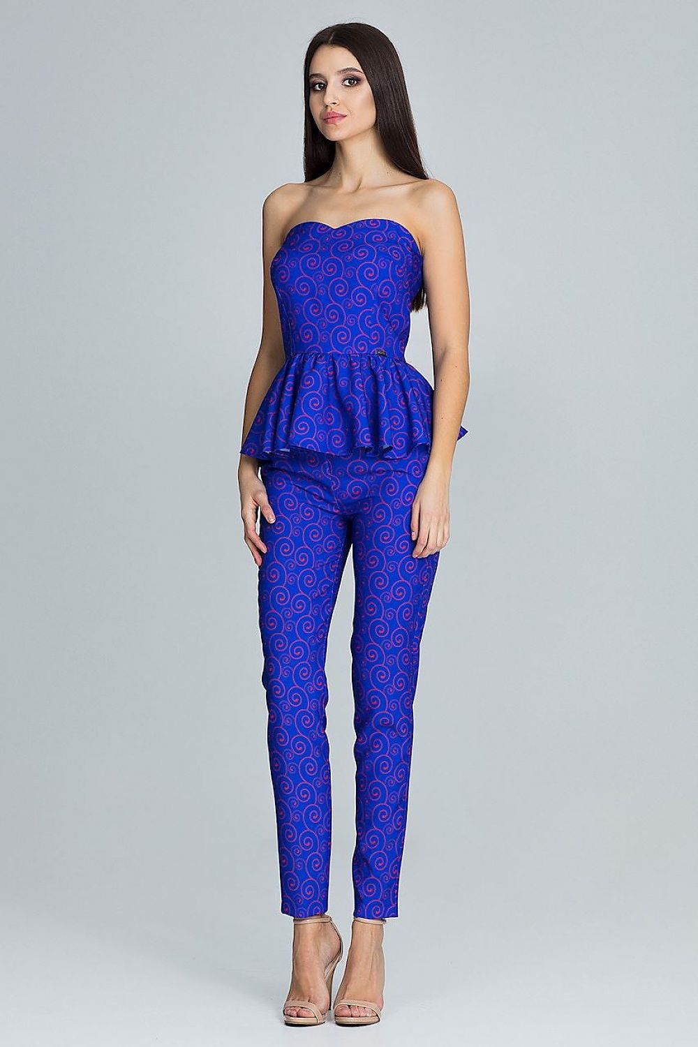 Woman wearing a blue patterned strapless top and pants on a gray background