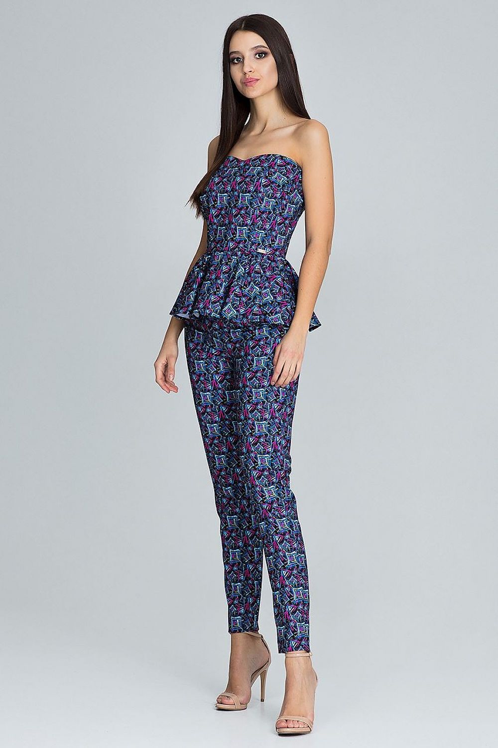 Woman wearing a strapless floral jumpsuit on a gray background