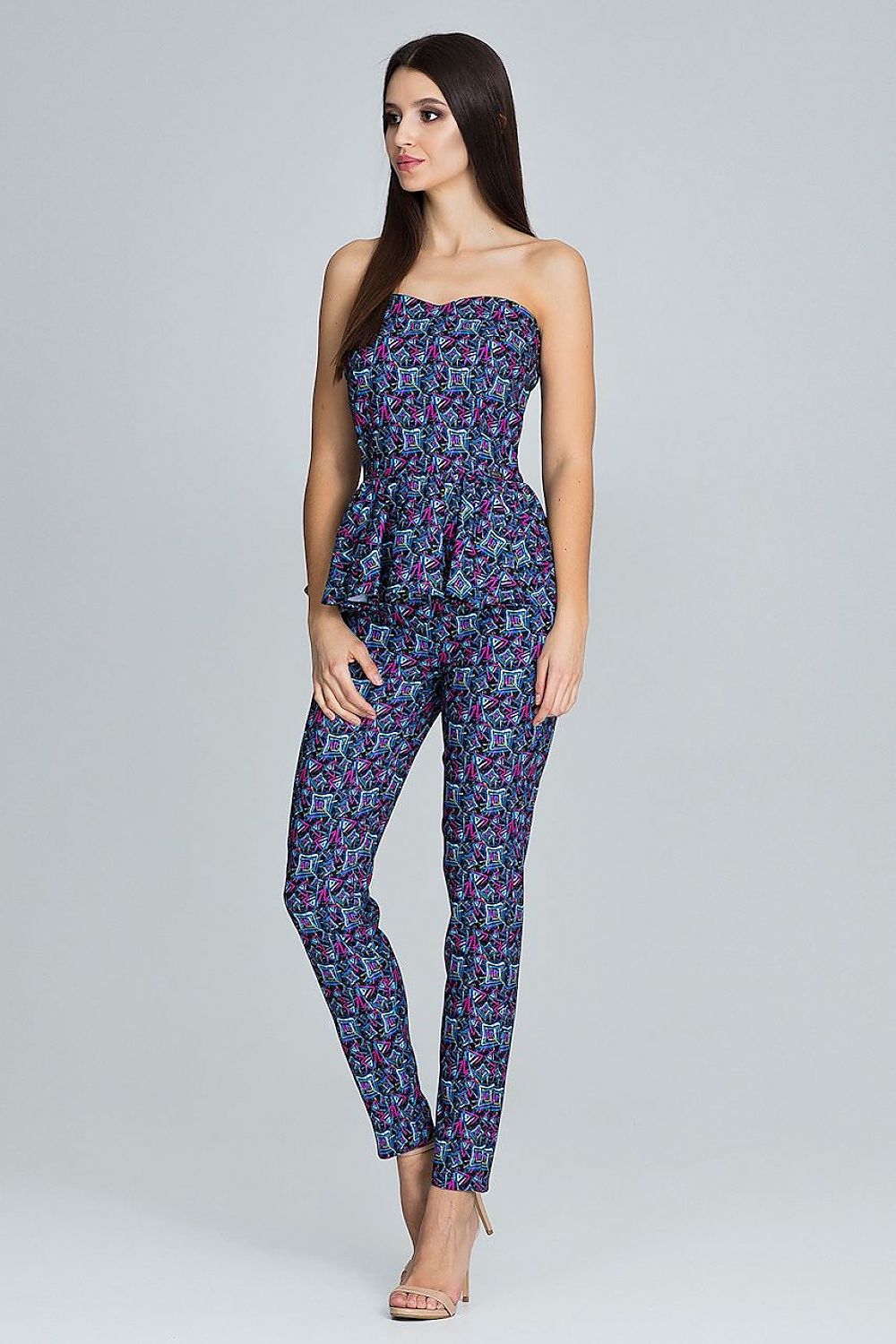 Woman wearing a strapless floral jumpsuit on a gray background