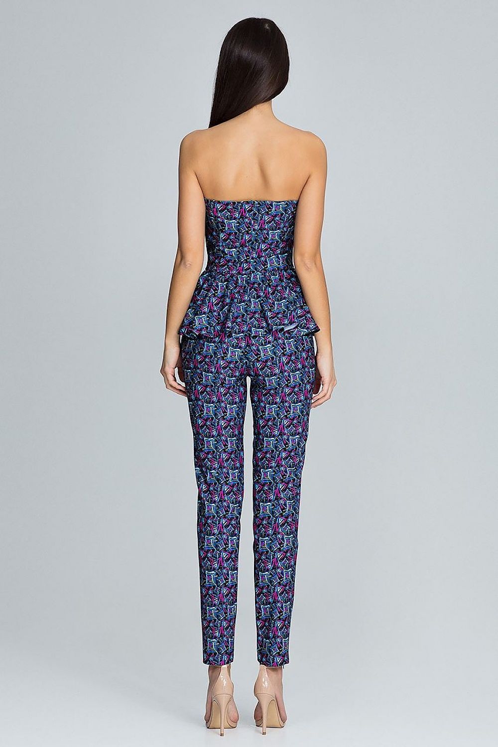 Woman wearing a strapless jumpsuit with a geometric pattern on a gray background
