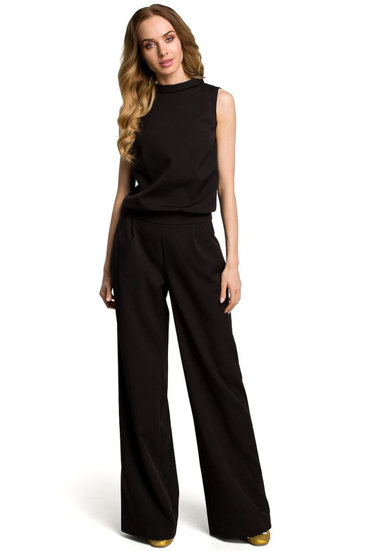 Woman wearing a black sleeveless top and wide-leg pants on a white background