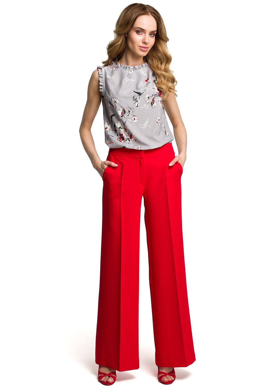 Woman wearing a floral top and red pants on a white background
