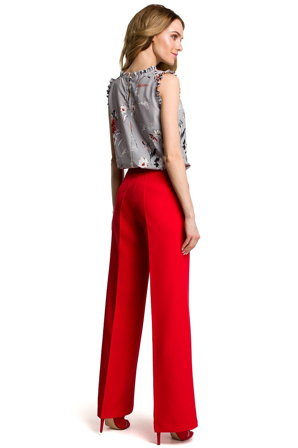 Woman wearing a patterned top and red pants on a white background