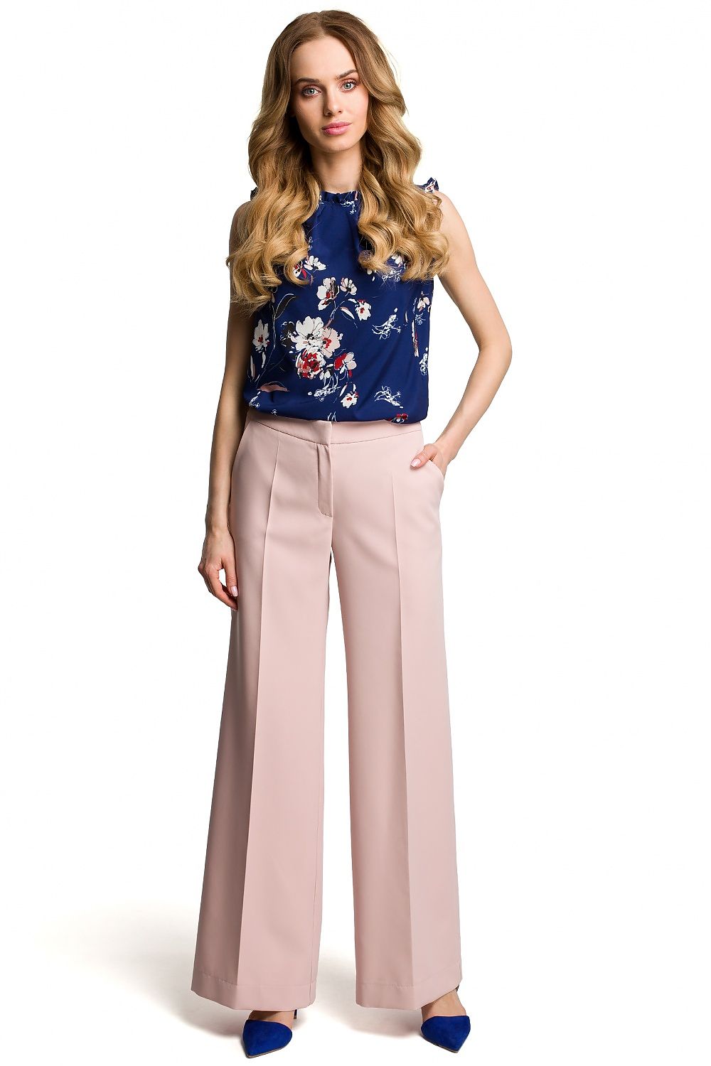 Woman wearing a floral top and beige pants on a white background