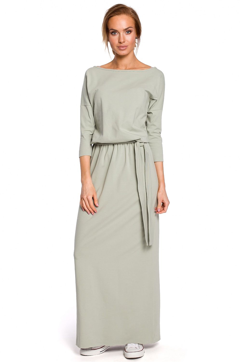 Woman wearing a long light green dress on a white background