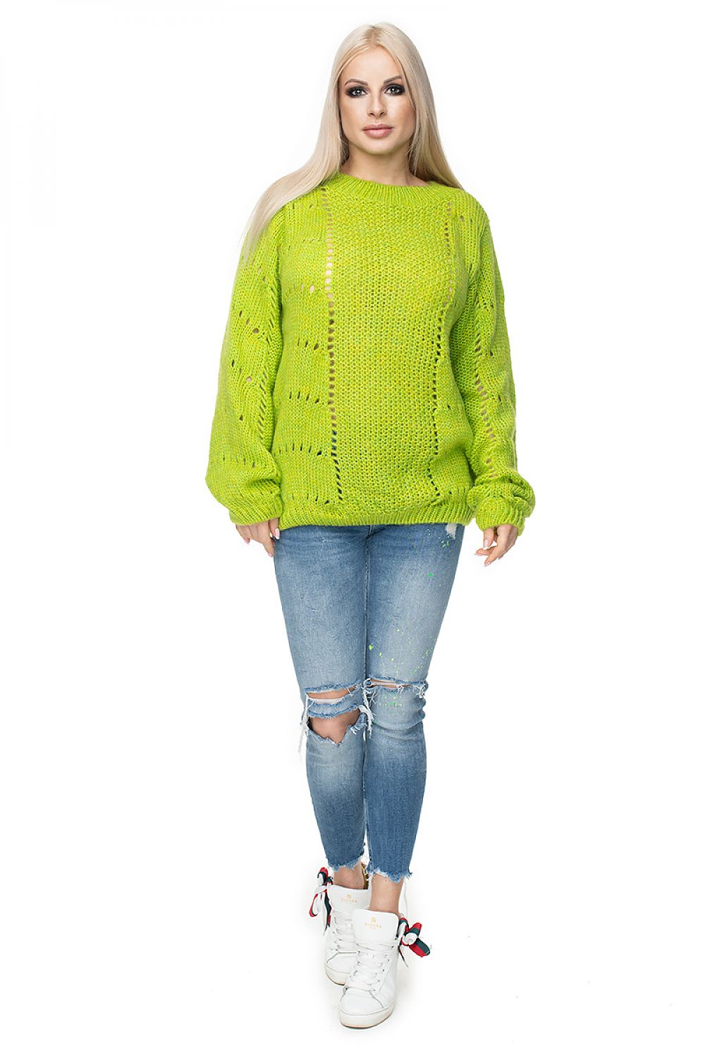 Person wearing a bright green sweater and blue jeans on a white background