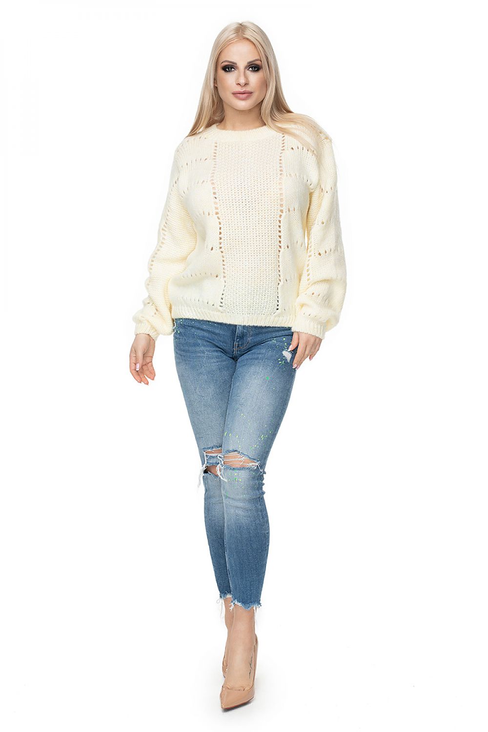 Woman wearing a cream sweater and blue jeans on a white background