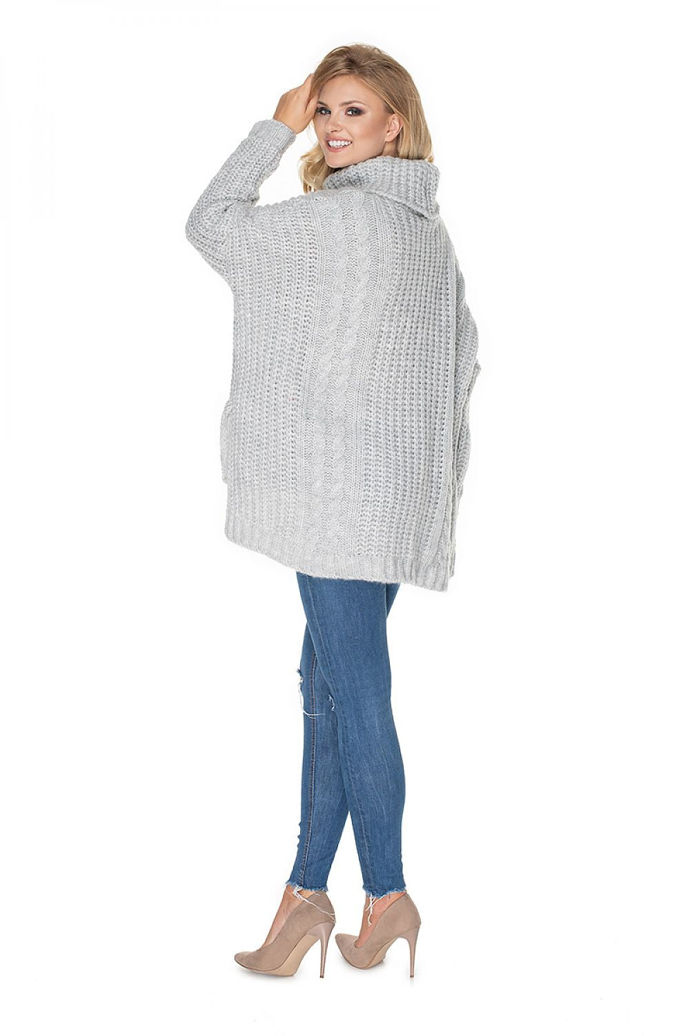 Woman wearing a gray knitted cardigan and blue jeans on a white background