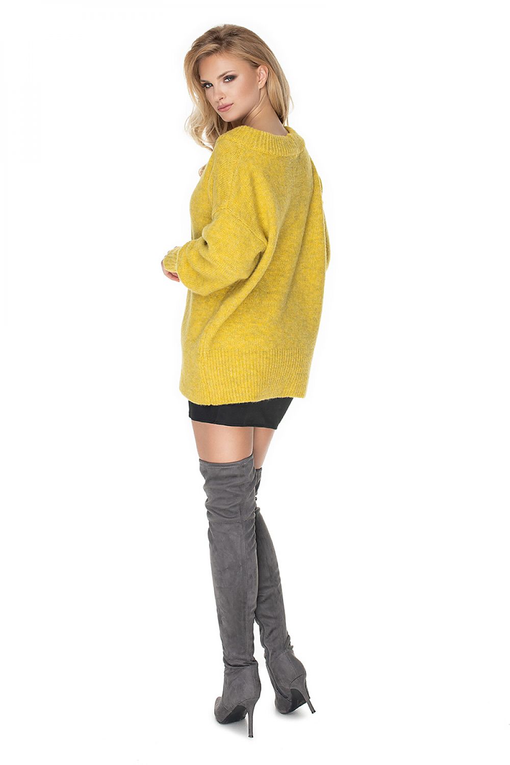 Woman wearing a yellow sweater and gray knee-high boots on a white background