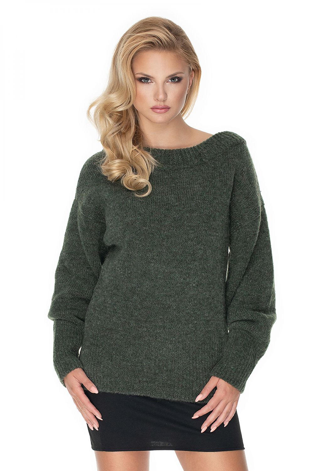 Woman wearing a green sweater over a black dress on a white background